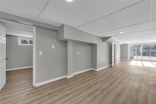 basement featuring light hardwood / wood-style floors and a paneled ceiling