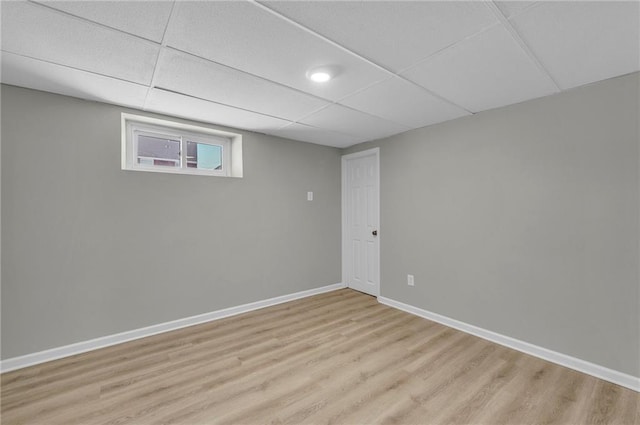 basement featuring a paneled ceiling and light hardwood / wood-style floors