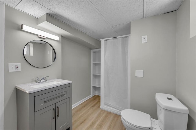 bathroom featuring a drop ceiling, a shower with shower curtain, hardwood / wood-style floors, toilet, and vanity