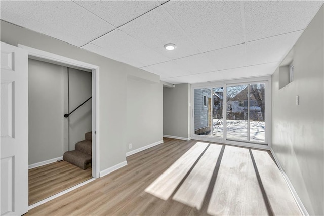 basement featuring a paneled ceiling and hardwood / wood-style flooring