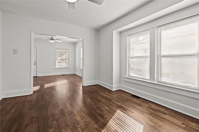 unfurnished room featuring ceiling fan, dark hardwood / wood-style floors, and a wealth of natural light