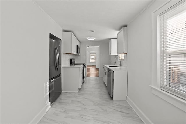 kitchen with stainless steel appliances, white cabinetry, sink, and crown molding