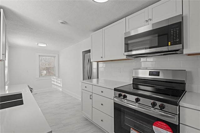 kitchen featuring decorative backsplash, a textured ceiling, white cabinets, and appliances with stainless steel finishes