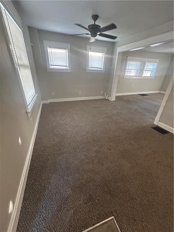 empty room featuring ceiling fan and dark carpet