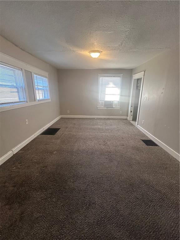 empty room with a textured ceiling and carpet