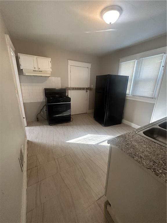 kitchen with sink, white cabinetry, and black fridge