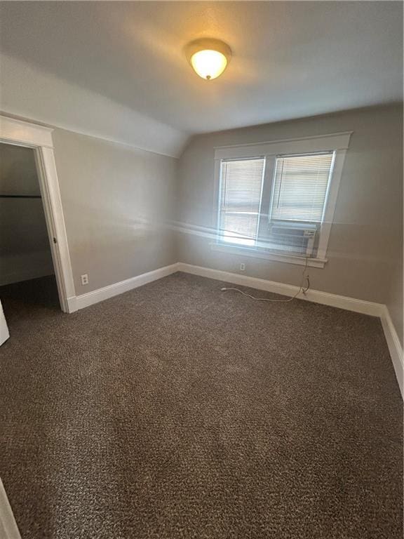 carpeted spare room featuring vaulted ceiling