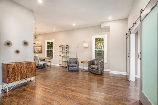 living area with a notable chandelier, a barn door, and dark hardwood / wood-style floors