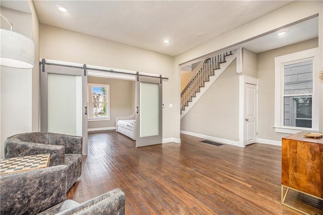 living room featuring a barn door and dark hardwood / wood-style floors