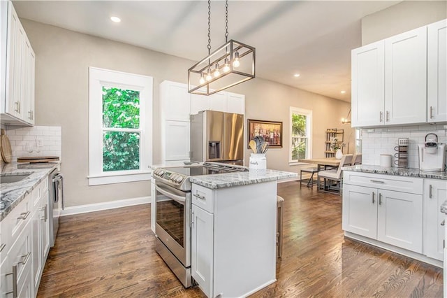 kitchen featuring stainless steel appliances, white cabinetry, tasteful backsplash, hanging light fixtures, and light stone countertops