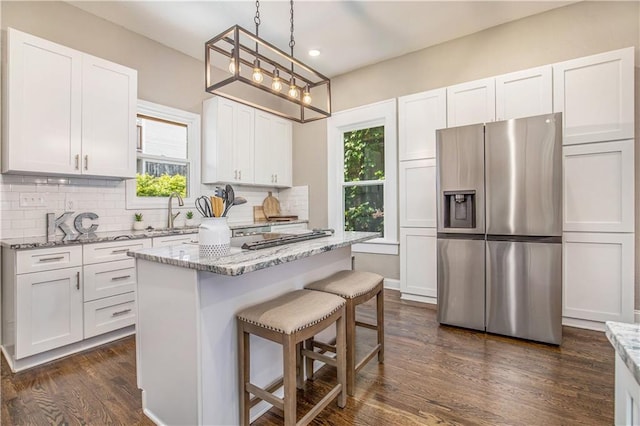 kitchen with light stone countertops, white cabinets, and stainless steel fridge