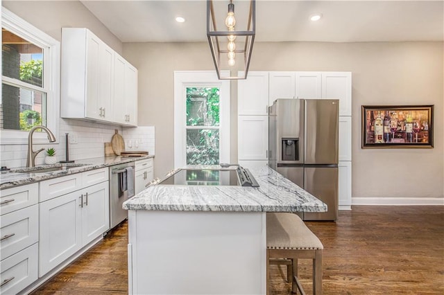 kitchen featuring stainless steel appliances, decorative light fixtures, a center island, and white cabinetry