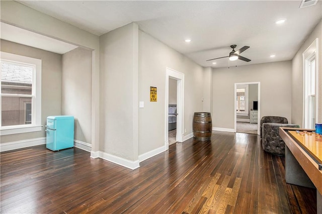 recreation room featuring ceiling fan, a wealth of natural light, and dark wood-type flooring