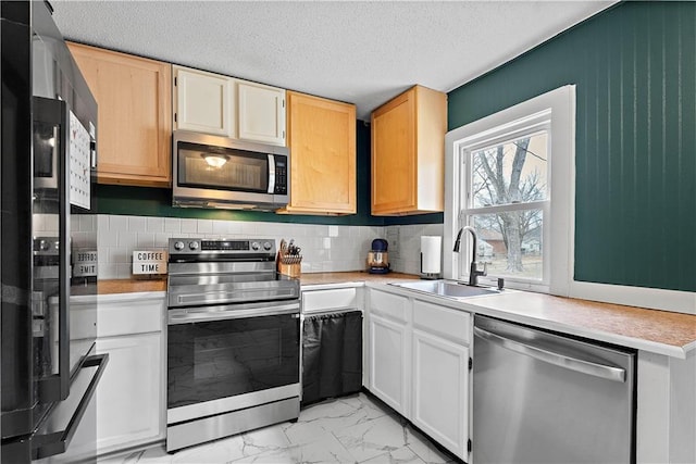 kitchen with stainless steel appliances, white cabinetry, sink, and decorative backsplash