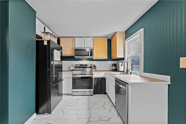 kitchen featuring appliances with stainless steel finishes, sink, white cabinets, and a textured ceiling