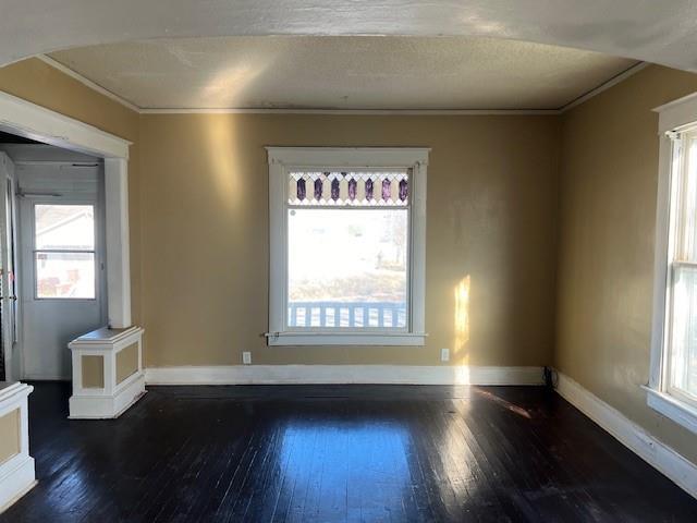 empty room with crown molding and dark wood-type flooring