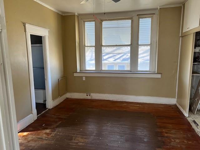 unfurnished bedroom featuring multiple windows, dark hardwood / wood-style floors, ceiling fan, and ornamental molding