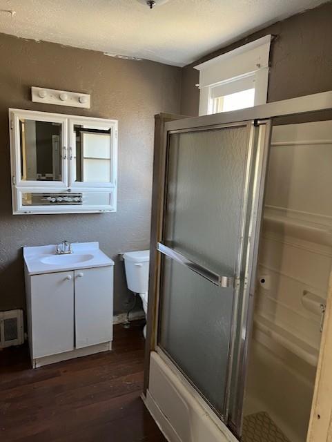 full bathroom featuring hardwood / wood-style flooring, vanity, toilet, and shower / bath combination with glass door