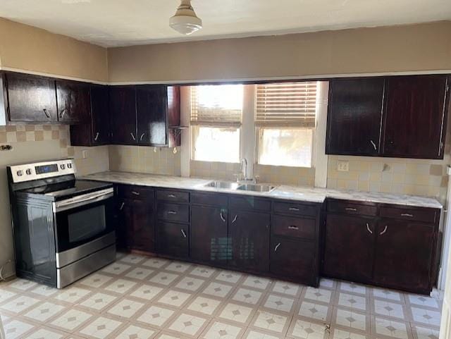 kitchen with decorative backsplash, dark brown cabinetry, stainless steel range with electric cooktop, and sink