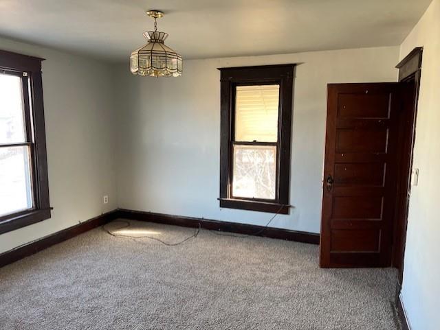 carpeted empty room with a chandelier