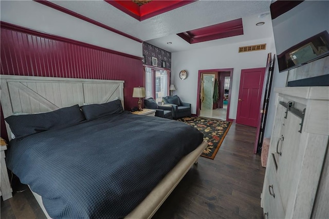 bedroom with dark wood finished floors, visible vents, and a tray ceiling