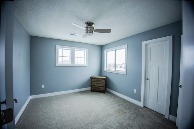 unfurnished bedroom featuring visible vents, baseboards, ceiling fan, carpet flooring, and a textured ceiling