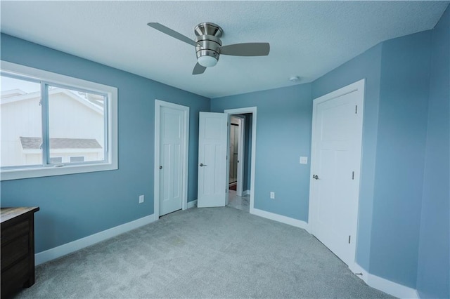 unfurnished bedroom featuring a textured ceiling, a ceiling fan, baseboards, and carpet floors