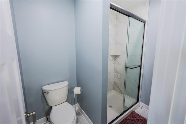 bathroom featuring baseboards, toilet, and a shower stall