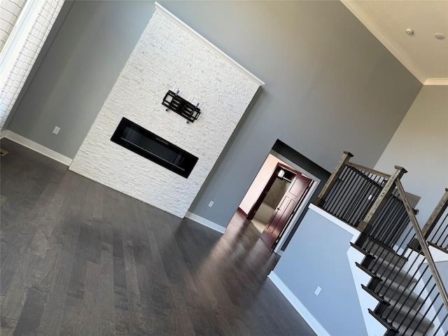 living area with a high ceiling, baseboards, and dark wood-style flooring