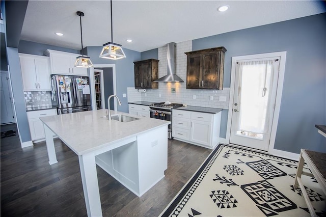 kitchen featuring dark wood-type flooring, a sink, a kitchen breakfast bar, stainless steel appliances, and wall chimney exhaust hood