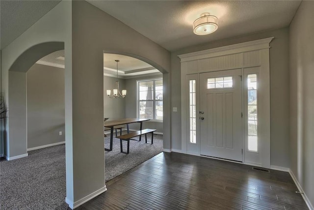 entryway featuring a tray ceiling, crown molding, dark hardwood / wood-style floors, and a chandelier