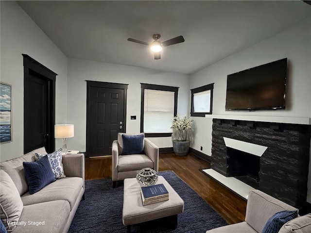 living room featuring ceiling fan, dark hardwood / wood-style floors, and a fireplace