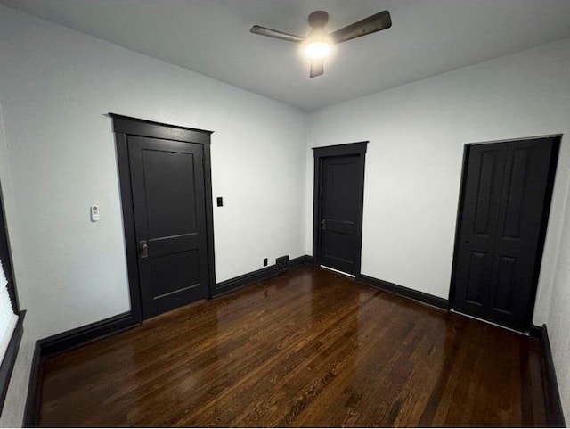 unfurnished bedroom featuring ceiling fan and dark hardwood / wood-style flooring