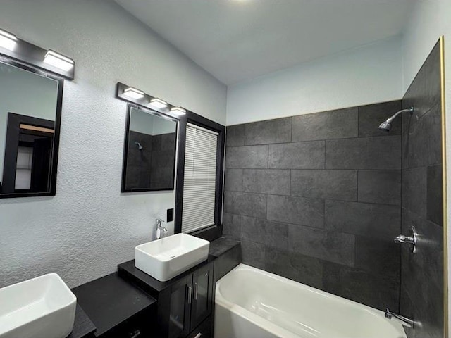 bathroom featuring tiled shower / bath and vanity