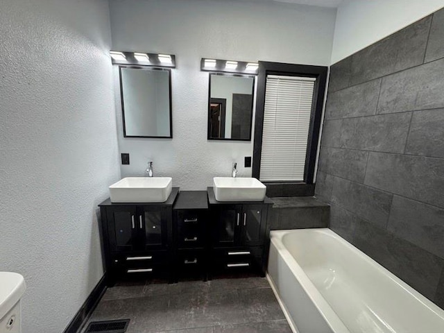 bathroom with toilet, a bath, and vanity