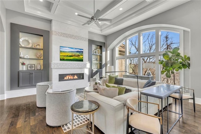 living room with ceiling fan, beamed ceiling, coffered ceiling, and built in shelves