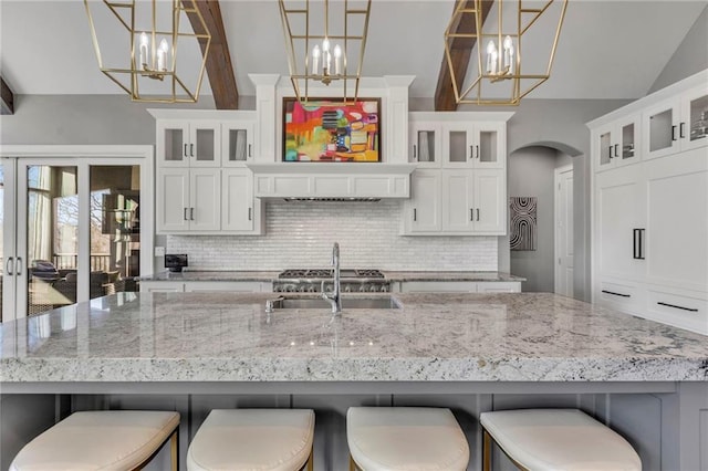 kitchen featuring hanging light fixtures, white cabinets, a kitchen bar, and backsplash