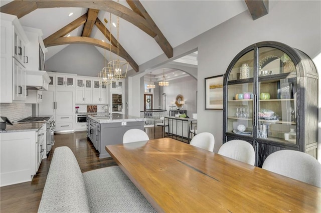 dining room featuring an inviting chandelier, dark hardwood / wood-style flooring, high vaulted ceiling, and beamed ceiling