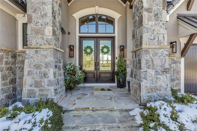 snow covered property entrance with french doors