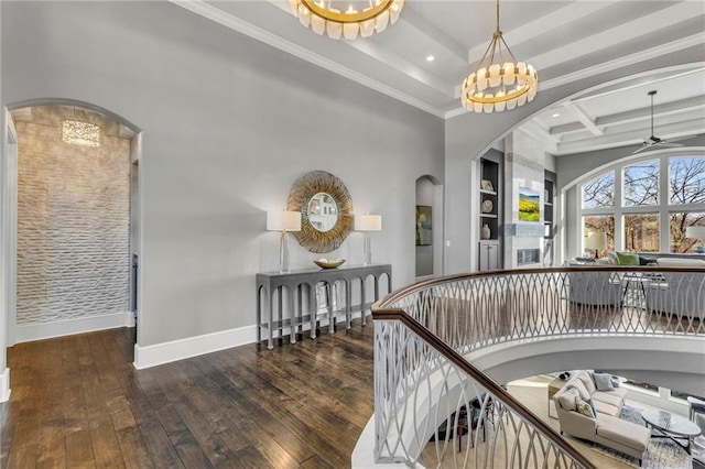 interior space featuring hardwood / wood-style floors, coffered ceiling, ornamental molding, ceiling fan with notable chandelier, and beamed ceiling