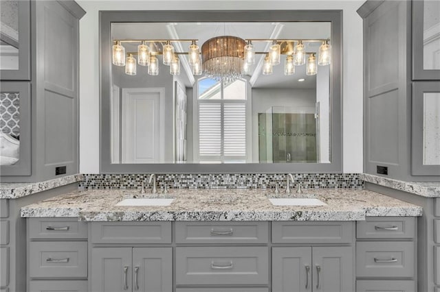 bathroom featuring vanity, a notable chandelier, and a shower with door