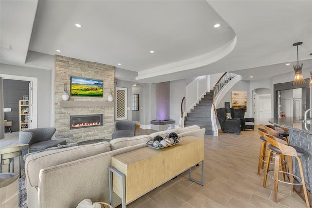 living room featuring a raised ceiling and a stone fireplace