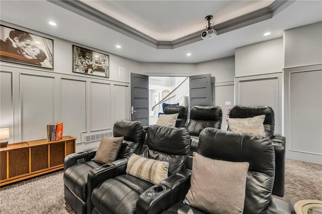 carpeted home theater room featuring ornamental molding and a tray ceiling