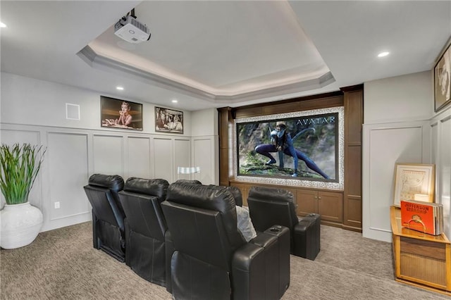 cinema room featuring a tray ceiling and light carpet