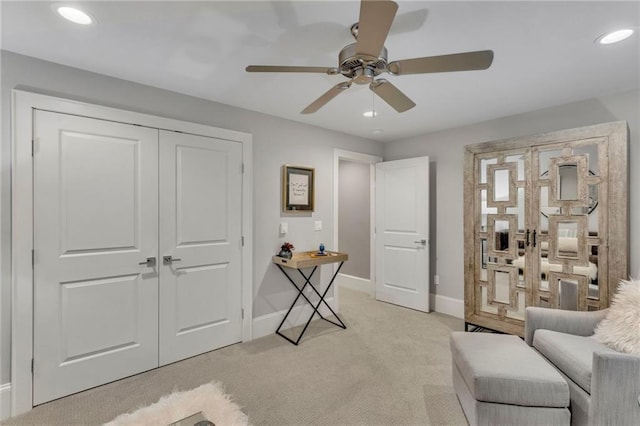 living area featuring light carpet and ceiling fan