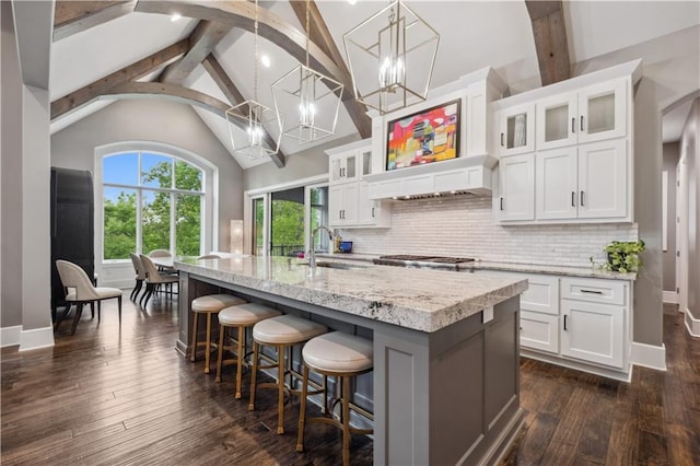 6069 Southlake Dr, Parkville, MO 64152 - kitchen featuring beamed ceiling, tasteful backsplash, white cabinets, a center island with sink, and dark wood finished floors