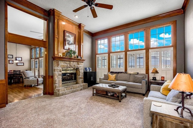 living room featuring ornamental molding, carpet floors, ceiling fan, and a fireplace