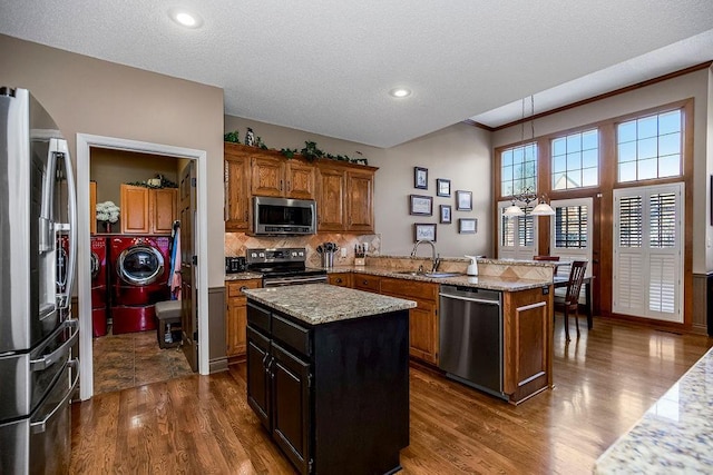 kitchen featuring stainless steel appliances, sink, a center island, light stone counters, and dark wood-type flooring