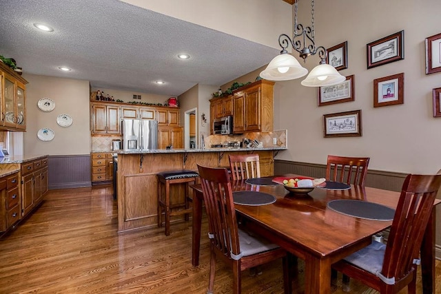 dining room with a textured ceiling and light hardwood / wood-style floors