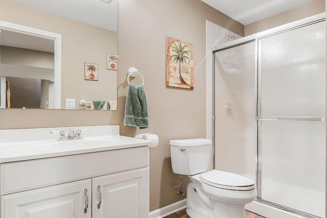 bathroom featuring toilet, a shower with shower door, and vanity